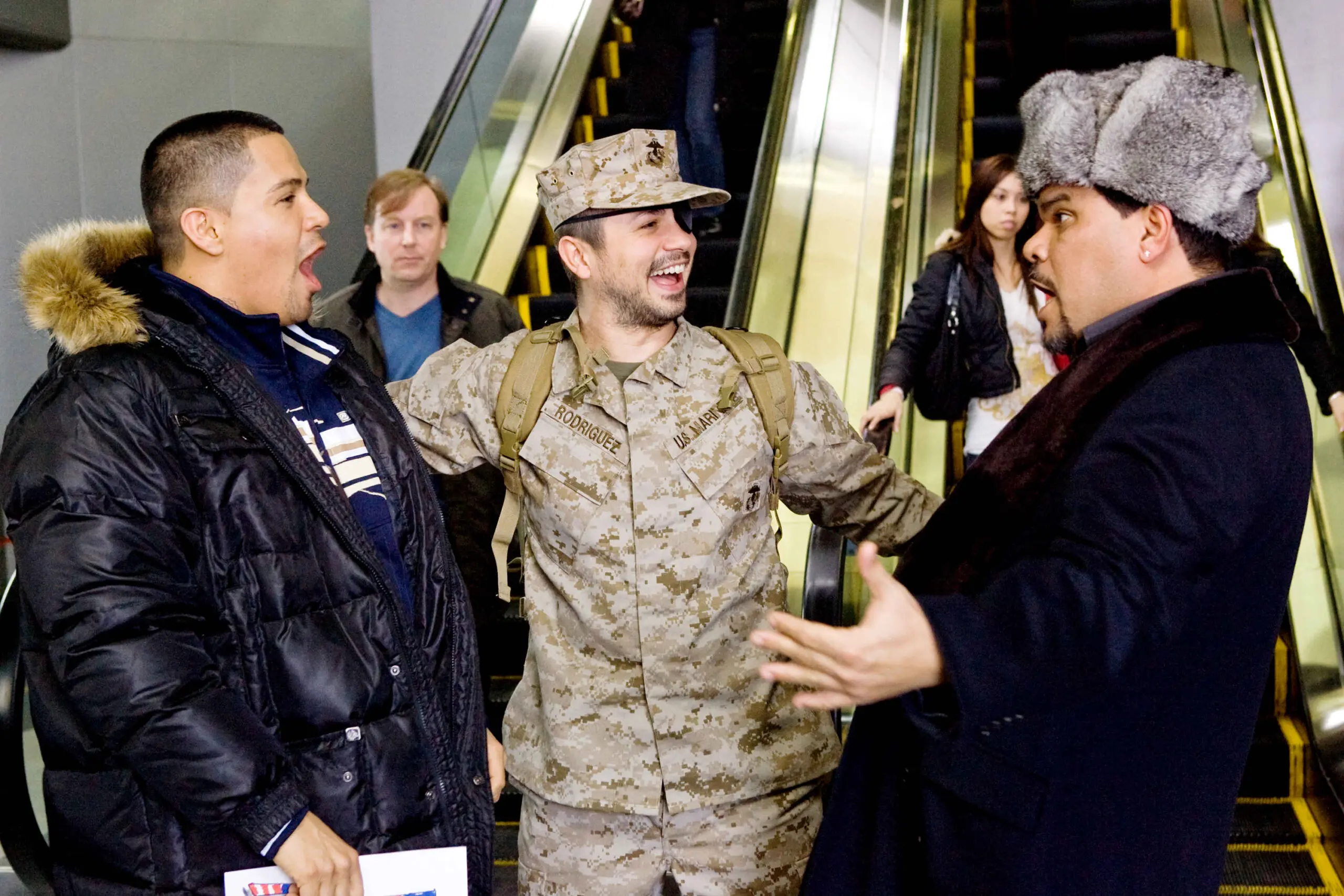 Man in military uniform joyfully greets two men near escalators
