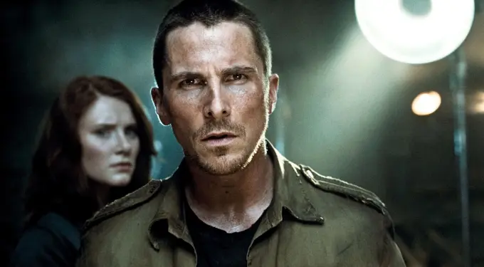 Christian Bale in military gear, intense expression, woman blurred behind