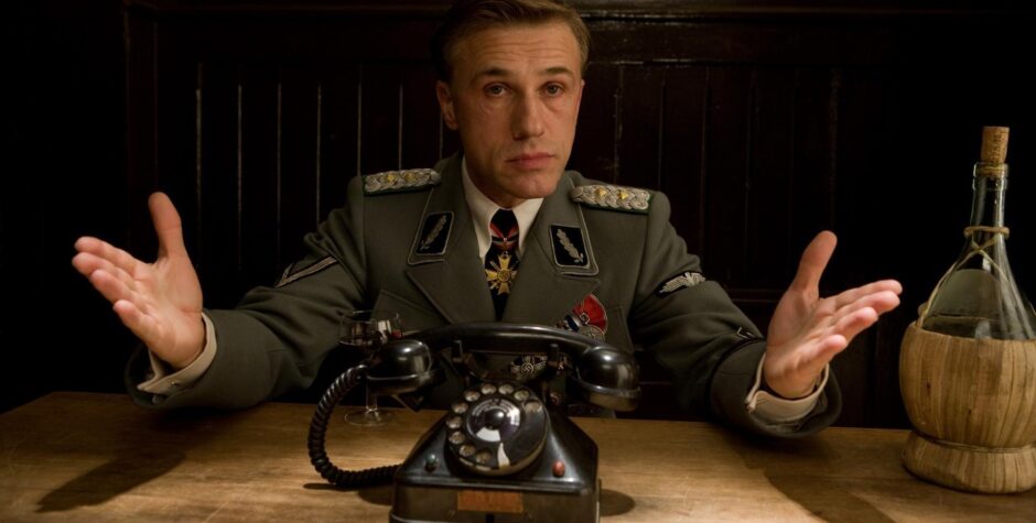 Christoph Waltz as Nazi officer gesturing at table with old phone