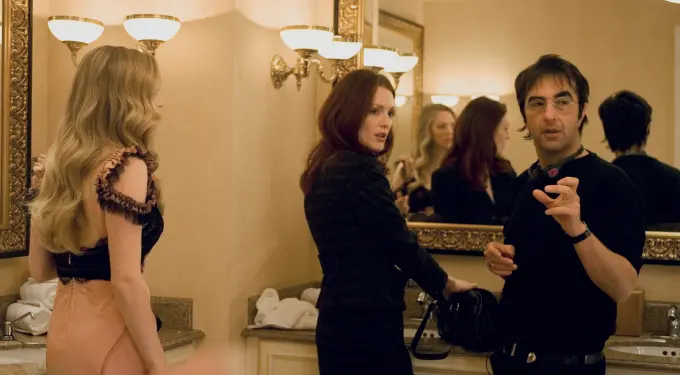 Two women and man converse in a bathroom with large mirror