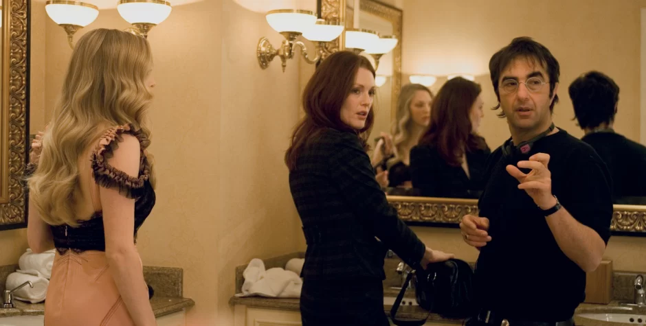Two women and man converse in a bathroom with large mirror