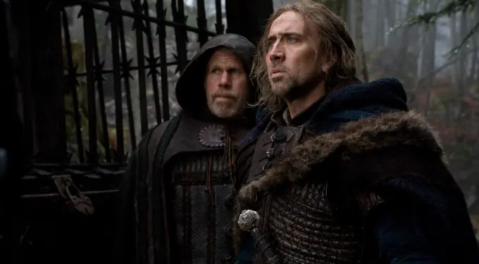 Ron Perlman and Nicolas Cage in medieval costumes near gate