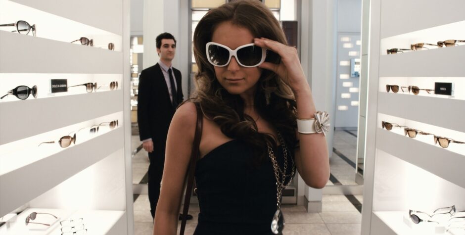 Alexa Vega trying on white sunglasses in a stylish eyewear store