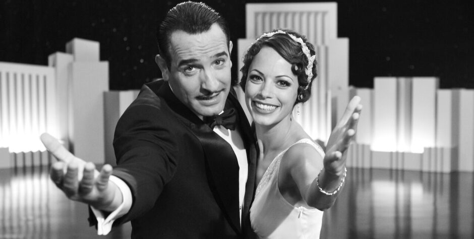 man and woman in 1920s attire smiling and reaching toward camera