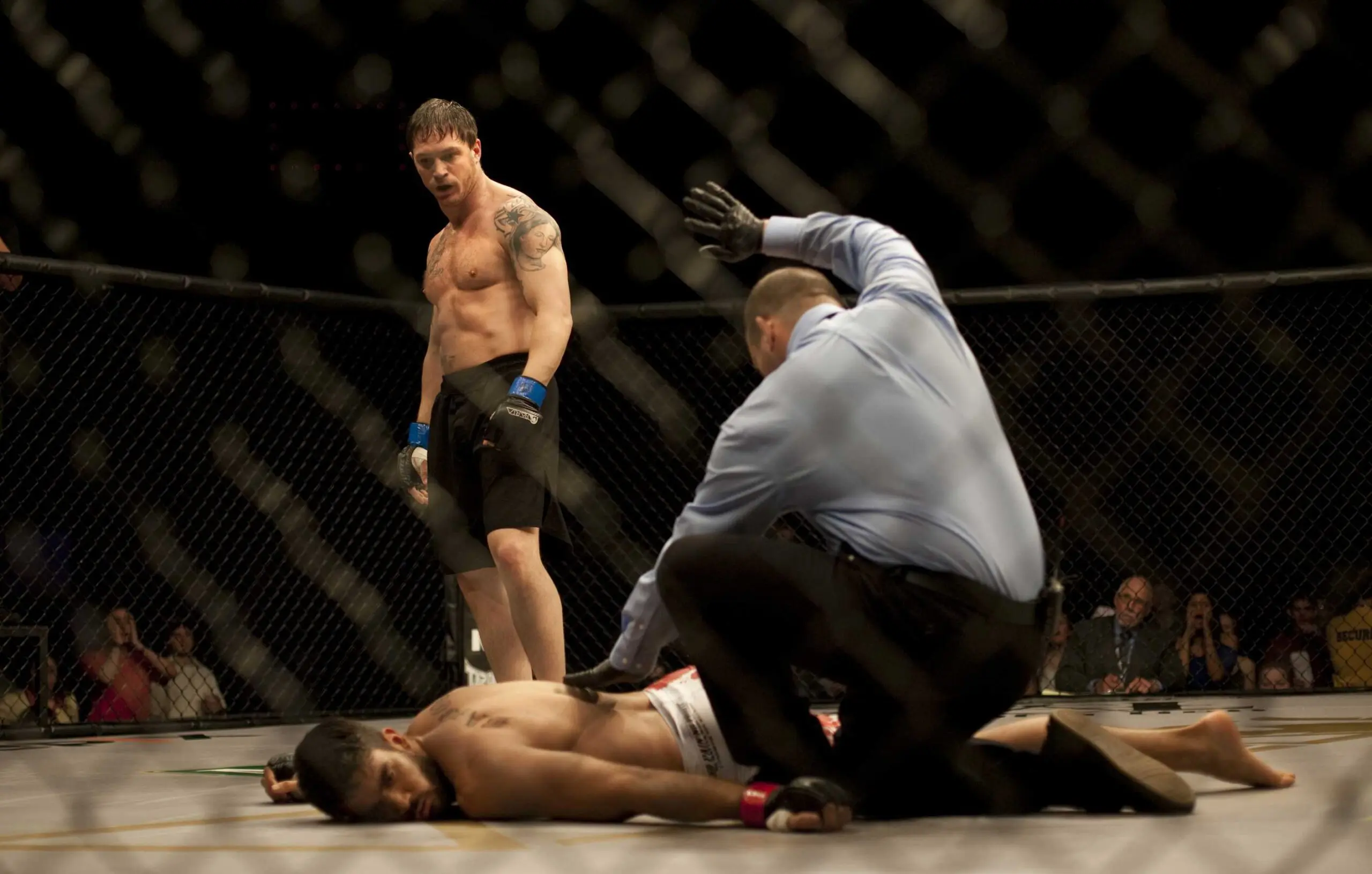 Tom Hardy and Joel Edgerton in MMA fight with referee in cage