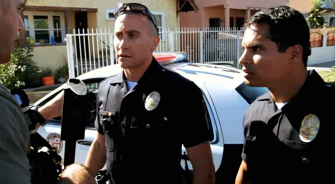 Two police officers stand in front of a patrol car during daytime