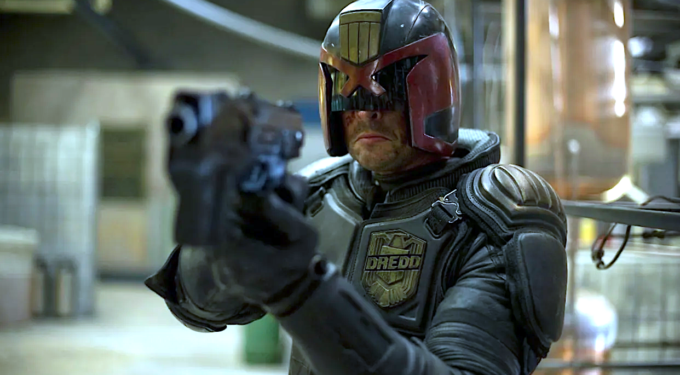 Karl Urban as the ‘Dredd’ aiming his gun in this action shot.
Karl Urban as Judge Dredd aiming gun in armored suit and helmet