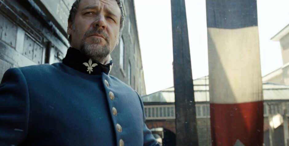 Man in blue military costume stands outside looking serious