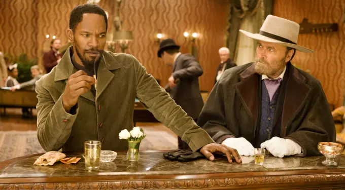 Jamie Foxx and Franco Nero sit at bar table in period western scene