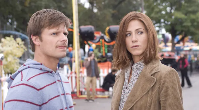 man in striped hoodie and woman in tan jacket at carnival outdoors
