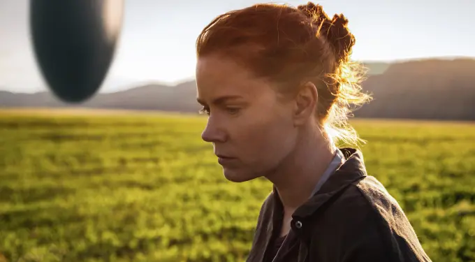 Amy Adams in a field looking serious, alien object behind her