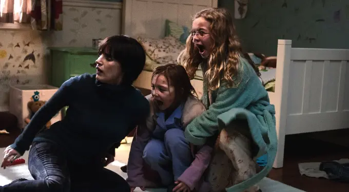 two girls and woman crouch, shouting, scared in dim bedroom