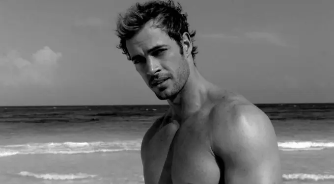 William Levy shirtless looking at camera with ocean background