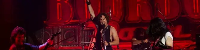 rock band performs on stage with singer raising arm and guitarist