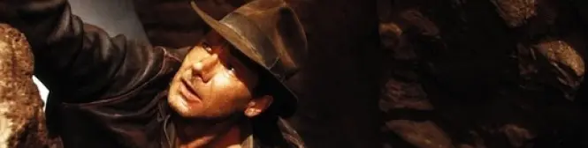 Man in brown fedora and leather jacket climbing in cave