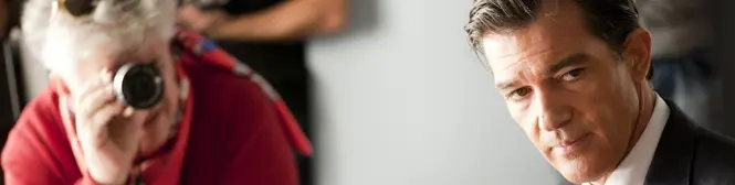 Man in suit with serious expression and blurred photographer behind
