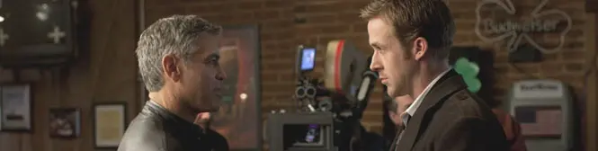Two men in a serious conversation indoors near film equipment
