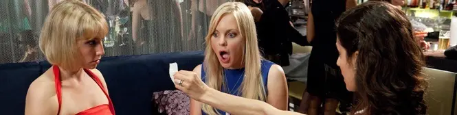three women react as one holds a small piece of paper