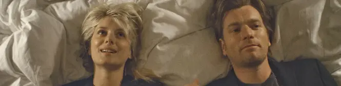 man and woman lying next to each other on bed looking up