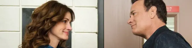 A man and woman face each other talking indoors in a movie scene