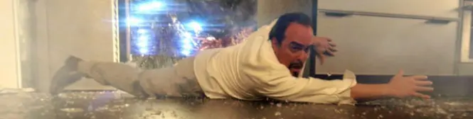 Man in white shirt sliding on floor with glass shards