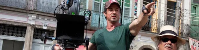 Man in green shirt pointing near film camera outdoors