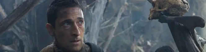 Man with dirt on his face looks up in a forest clearing