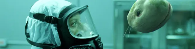 person in hazmat suit looks at floating alien creature in lab