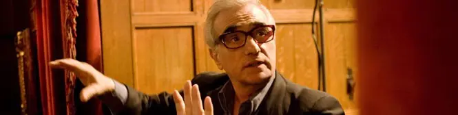 Man with glasses gestures during a conversation indoors