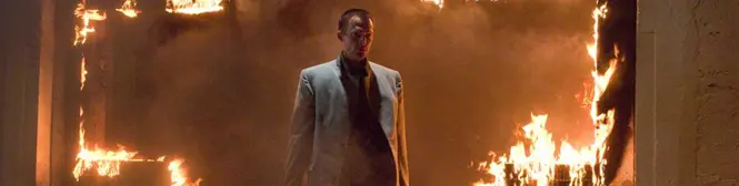Man in suit stands in fiery room, intense scene from Legion