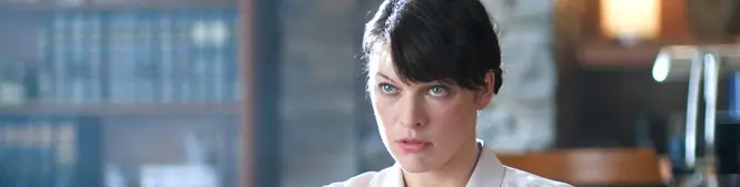 woman with dark hair and serious expression indoors at desk
