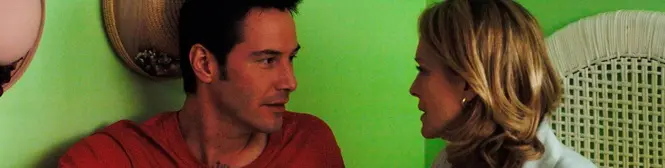 Man and woman talk closely against a green wall indoors