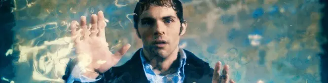 Man underwater pressing hands to surface looking directly at camera