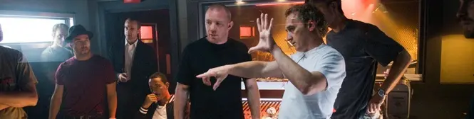 man gestures directing actors while others listen on film set