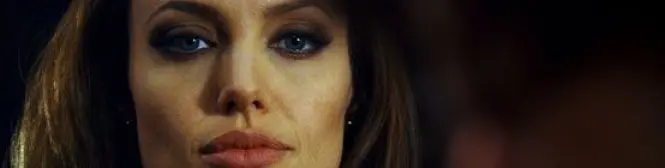 close-up of a woman with brown hair and blue eyes looking serious