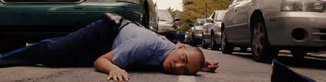 Man in police uniform laying face down on a city street