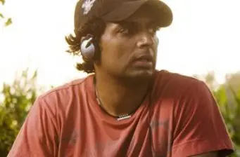 Director M. Night Shyamalan outdoors wearing a cap and headphones