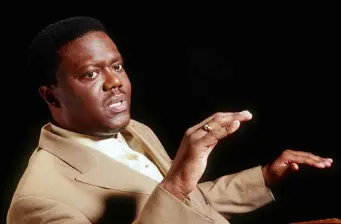 Bernie Mac in tan suit gesturing during a studio portrait