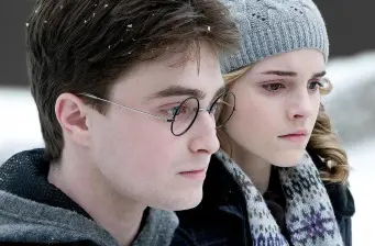 young man with glasses and woman in knit hat outdoors in snow
