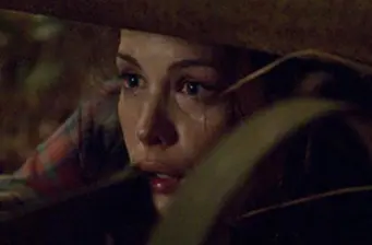 Woman with fearful expression hiding in darkness, tense moment