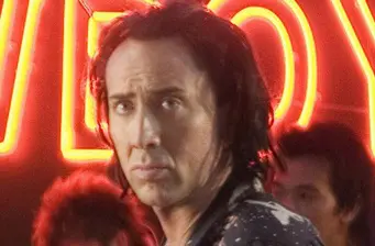 Close-up of serious man with long hair under red neon light