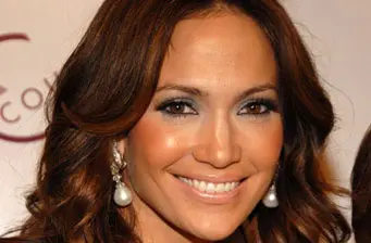 Jennifer Lopez smiling close-up with pearl earrings and styled hair