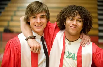 Two young men in red graduation gowns smiling and posing together