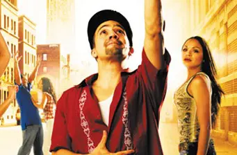 Lin-Manuel Miranda pointing up in outdoor scene from In the Heights