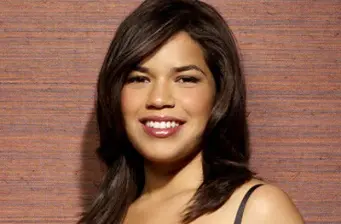 Headshot of America Ferrera smiling against brown background