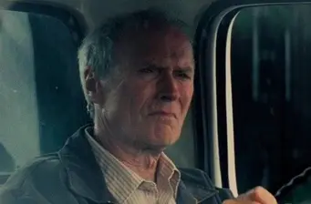 Clint Eastwood close-up inside a vehicle looking serious