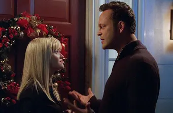 Man and woman speak by a Christmas wreath on door