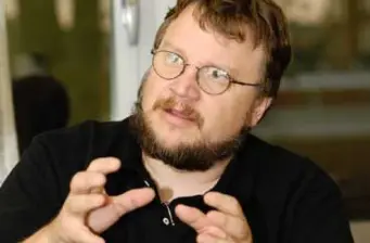 Bearded man with glasses gesturing while talking indoors