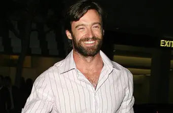 Hugh Jackman smiling in a striped shirt at night