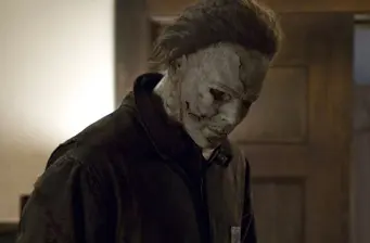 Michael Myers in mask looking down in dimly lit room